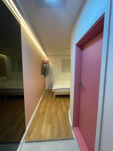 korytarz z różowymi drzwiami i kanapą w pokoju w obiekcie SSH LK Hostel w Seulu