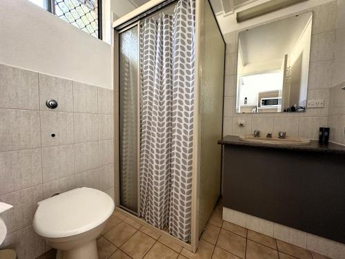a bathroom with a shower with a toilet and a sink at Sunflower Motel in Warialda