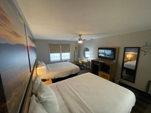 a hotel room with two beds and a flat screen tv at Days Inn by Wyndham Holladay in Holladay