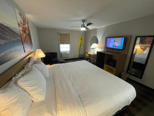a hotel room with a bed and a flat screen tv at Days Inn by Wyndham Holladay in Holladay