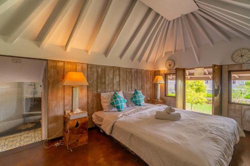 a bedroom with a large white bed with blue pillows at Four Monkeys House in Bedugul