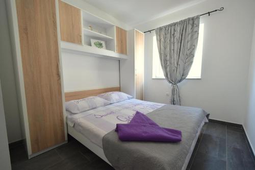 een slaapkamer met een bed met een paarse handdoek erop bij Apartment Bianca in Čižići