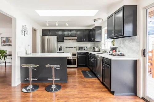 eine Küche mit schwarzen Schränken und eine Kücheninsel mit Barhockern in der Unterkunft Shiny Rambler House with Spacious Solarium. in Everett