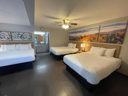 a hotel room with two beds and a ceiling fan at Days Inn by Wyndham Holladay in Holladay