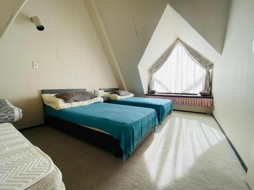 two beds in a room with a large window at ザ・ヴィレッジアルファ in Tomamu