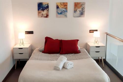 a bedroom with a bed with red pillows and two lamps at Loft para soñar y explorar Madrid entero para tí! in Madrid