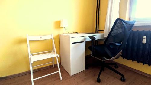 a desk and a chair next to a desk with a lamp at Seaside Apartment in Gdańsk