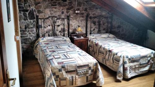 a bedroom with two beds and a stone wall at La Solana de Babia in Torrestío
