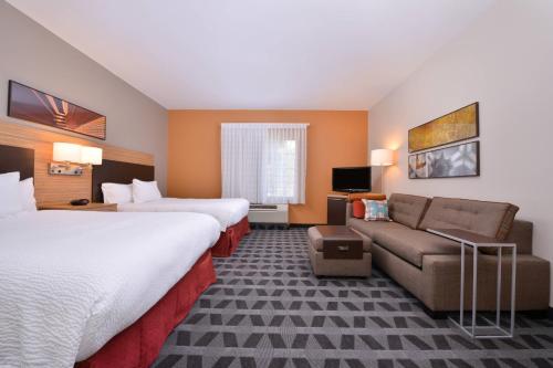 a hotel room with two beds and a couch at TownePlace Suites by Marriott Ontario Airport in Rancho Cucamonga