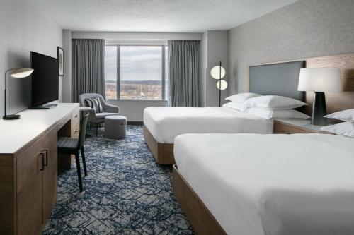 a hotel room with two beds and a television at Sheraton Overland Park Hotel at the Convention Center in Overland Park