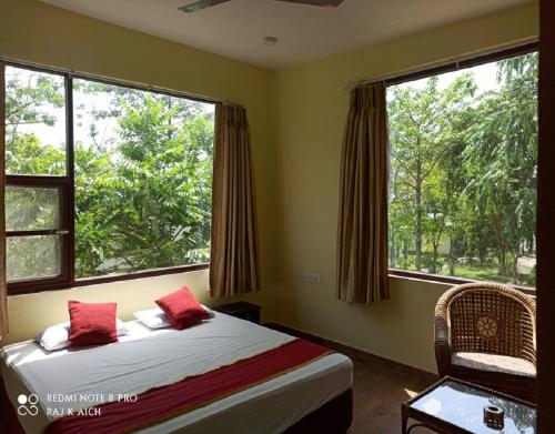 a bedroom with a bed and two large windows at Nalgarh Retreat - JUNGLE RESORT by StayApart in Uttar Simlabari