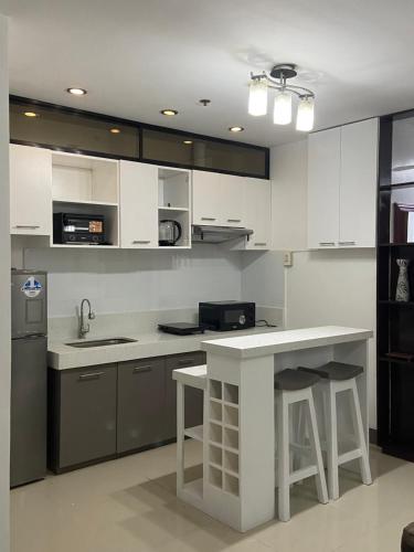 a kitchen with white cabinets and a counter with stools at CDO UPTOWN CONDOMINIUM in Cagayan de Oro