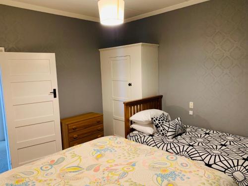 um quarto com uma cama, uma cómoda e um armário em Quiet home with modern touch em Dunedin