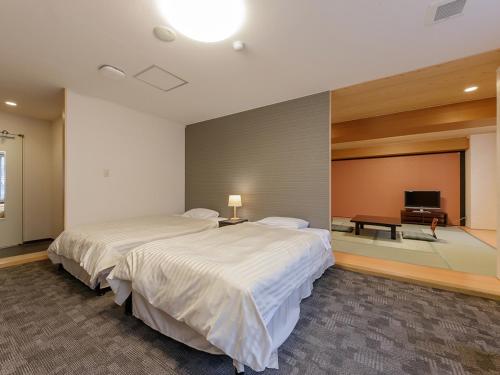Itoen Hotel Shiobara في ناسوشيوبارا: غرفة نوم بسرير كبير وتلفزيون