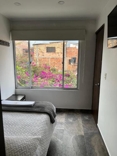 a bedroom with a window view of a flower garden at Hotel San Martin Mosquera in Mosquera
