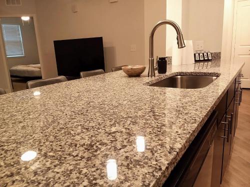 a kitchen with a granite counter top and a sink at "Two Bella" Luxury Apt - POOL - 4 Mi to Beach in Daytona Beach