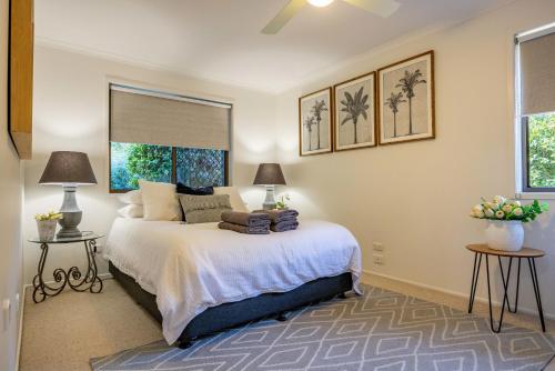 a bedroom with a bed with two tables and two windows at Teak Street Retreat - Ultimate Comfort Steps to Maleny Main Street in Maleny