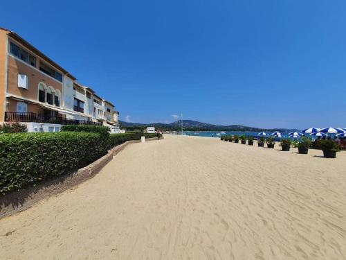 a sandy beach next to a building and the ocean at Les Golfes Clairs in Grimaud