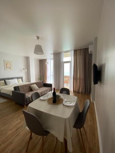 uma sala de estar com uma mesa e cadeiras e um sofá em Apartments LUNA em Kobuleti