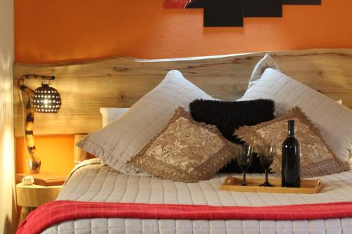 1 cama con cabecero de madera y copas de vino en Chalé Refúgio do Pavão en Visconde De Maua