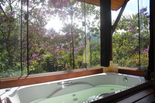 a bath tub in a room with a window at Chalé Refúgio do Pavão in Visconde De Maua