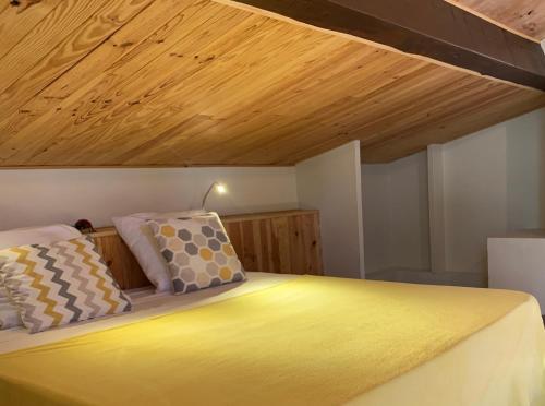 - une chambre avec un lit jaune et un plafond en bois dans l'établissement Chambre d'hôtes climatisée avec terrasse et spa, à Saint Alban Auriolles