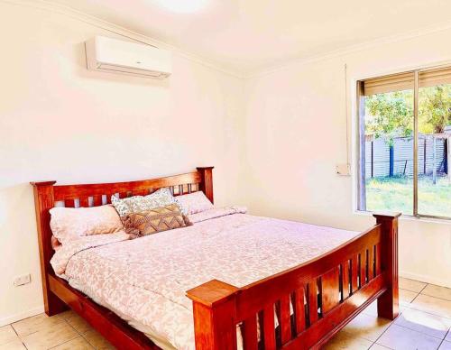 sypialnia z dużym drewnianym łóżkiem i oknem w obiekcie Grabber- Three bedroom charm in Alice Springs w mieście Alice Springs