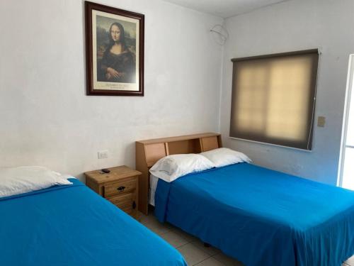 ein Schlafzimmer mit 2 Betten und einem Bild an der Wand in der Unterkunft Estancia Santa Fe in Celaya