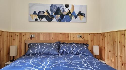 a bedroom with a blue bed with a painting on the wall at Appartamento Val di Luce Relax Cristallo in Abetone