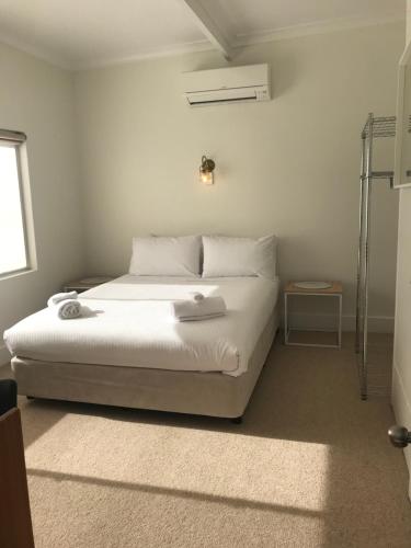 a bedroom with a bed with white sheets and a window at Billabong Wangaratta in Wangaratta