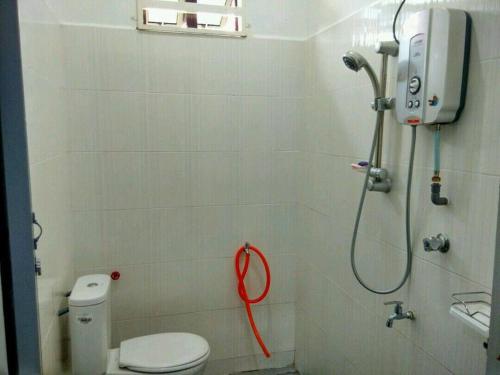 La salle de bains est pourvue d'une douche et de toilettes avec un tuyau rouge. dans l'établissement KUALA TERENGGANU GUESTHOUSE-FREE WIFI-NEAR NASI DAGANG ATAS ToL UNIT B- 2 BILIK AIRCOND DAN 1 BILIK KIPAS, à Kuala Terengganu