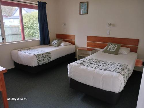 a hotel room with two beds and a window at Anatoki Lodge Motel in Takaka
