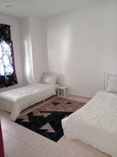 um quarto branco com 2 camas e uma janela em Cherating Damai Guest House em Cherating