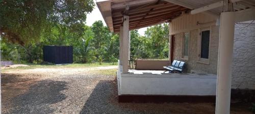 un banco sentado en el porche de una casa en Lake Lodge Weeravila, en Hambantota