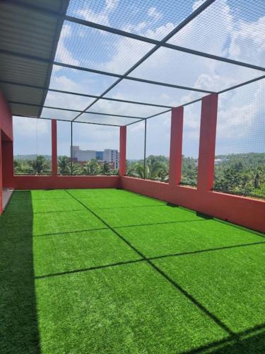 a large room with green grass and a roof at Gulzar 2BHK Service Apartment, kannur in Kannur