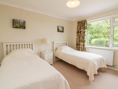 two beds in a bedroom with a window at 7 Old Rectory Gardens in Kingsbridge
