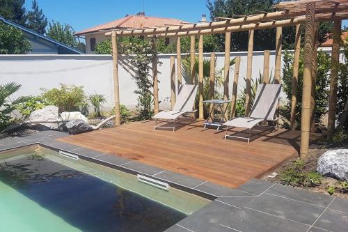 a wooden deck with chairs next to a swimming pool at Cosy villa with pool near ocean in Labenne