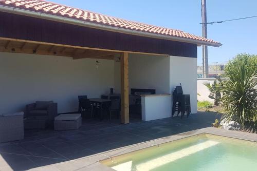 a patio with a table and chairs and a pool at Cosy villa with pool near ocean in Labenne