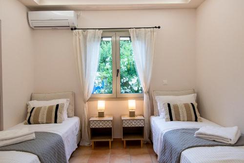 two beds in a room with a window at The courtyard in Skala Eresou