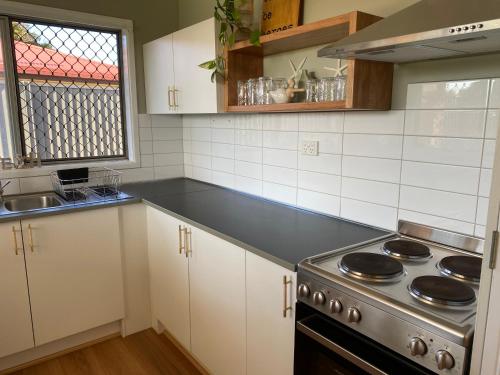 a kitchen with white cabinets and a stove top oven at Walk to beach - 3bed House - Pet & kid friendly in Buddina
