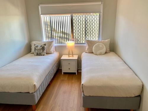 two twin beds in a room with a window at Walk to beach - 3bed House - Pet & kid friendly in Buddina