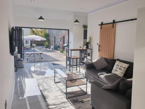 a living room with a couch and a table at The Studio, Luxury Modern Apartment in The South Hams, Stunning walks on the doorstep, a 20 minute drive to the beautiful sandy beaches, quiet courtyard setting, Shops, Bars and Restaurants a short walk away! in Ivybridge
