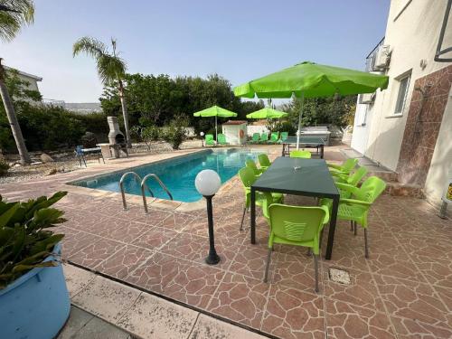 a patio with a table and green chairs next to a pool at Villa Coralia Gardens 1km From Coral Bay Beach in Coral Bay