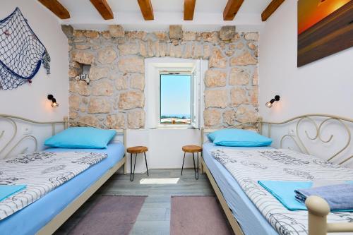 two beds in a room with a window at Stone House Biskup in Babino Polje