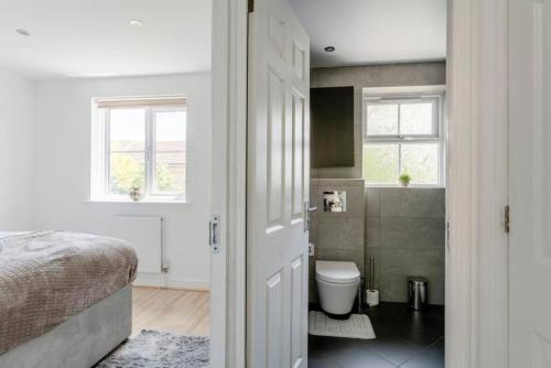 a bedroom with a bed and a bathroom with a toilet at Lovegrove House - Modern 3 bed house for business or family stay with free parking in Slough