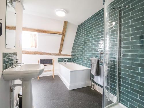 a bathroom with a tub and a sink and a bath tub at South Grange Cottage in Saxmundham