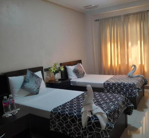 two beds in a hotel room with swans on them at HilFrans Lodge in Vigan