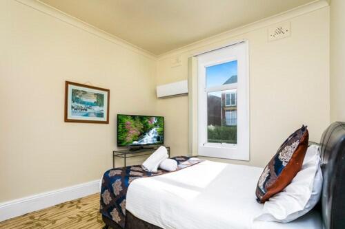 a bedroom with a bed and a window at The North Shore Hotel in Sydney