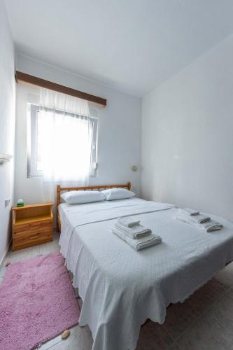 a bedroom with a large white bed with a pink rug at Spacious seaside house in Nea Potidaea