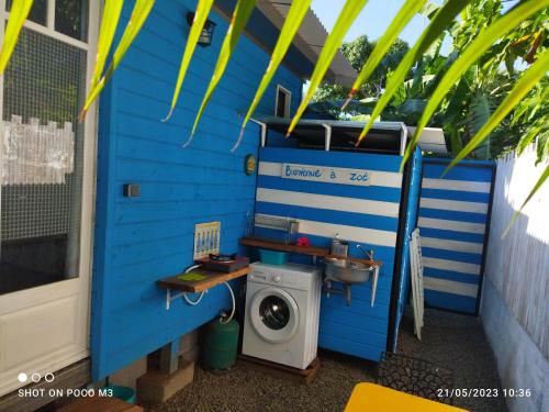ein blaues Haus mit einer Waschmaschine und einem Waschbecken in der Unterkunft Bungalow bleu in L’Étang-Salé